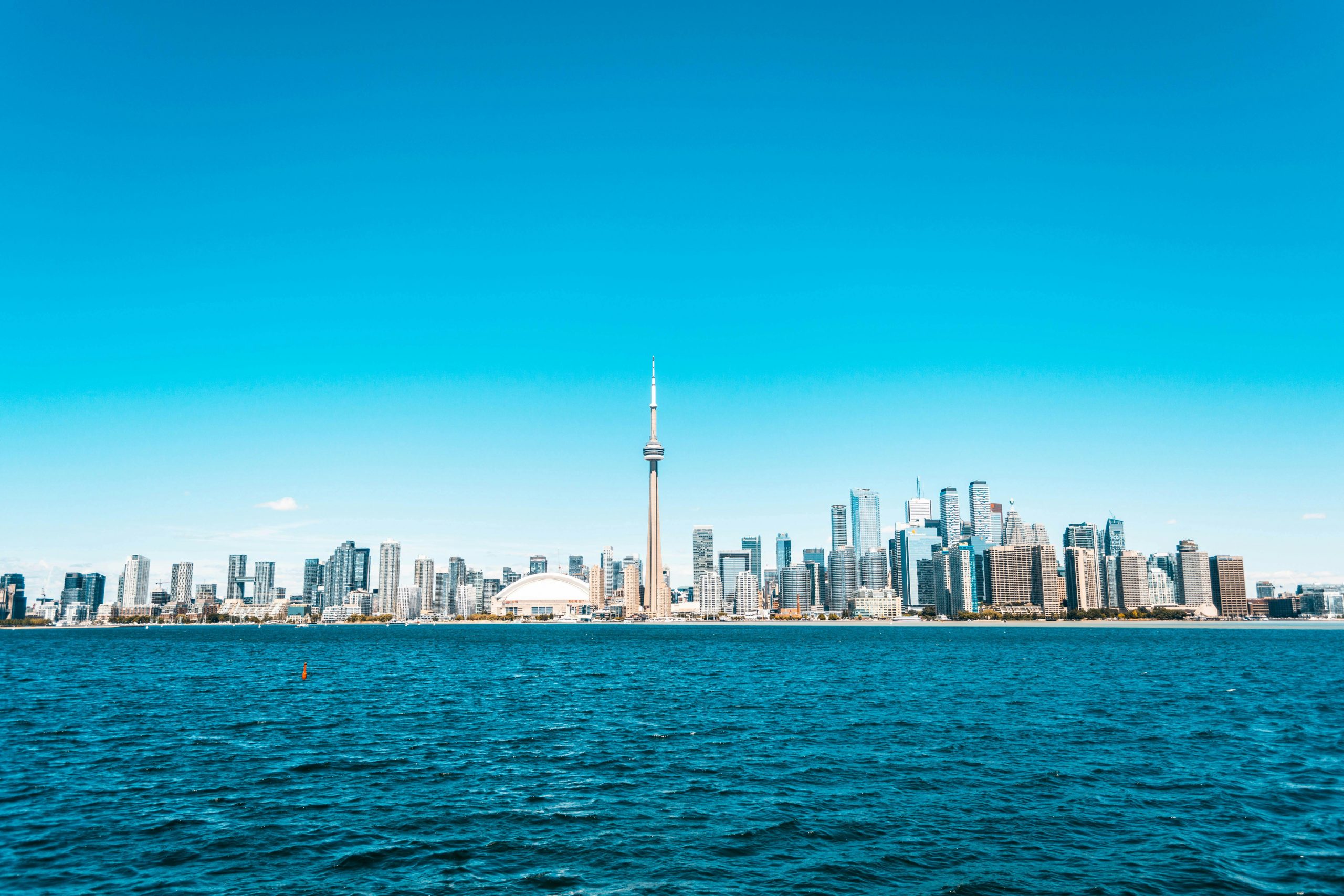 Beautiful view of Toronto skyline featuring the iconic CN Tower and vibrant blue waterfront.
